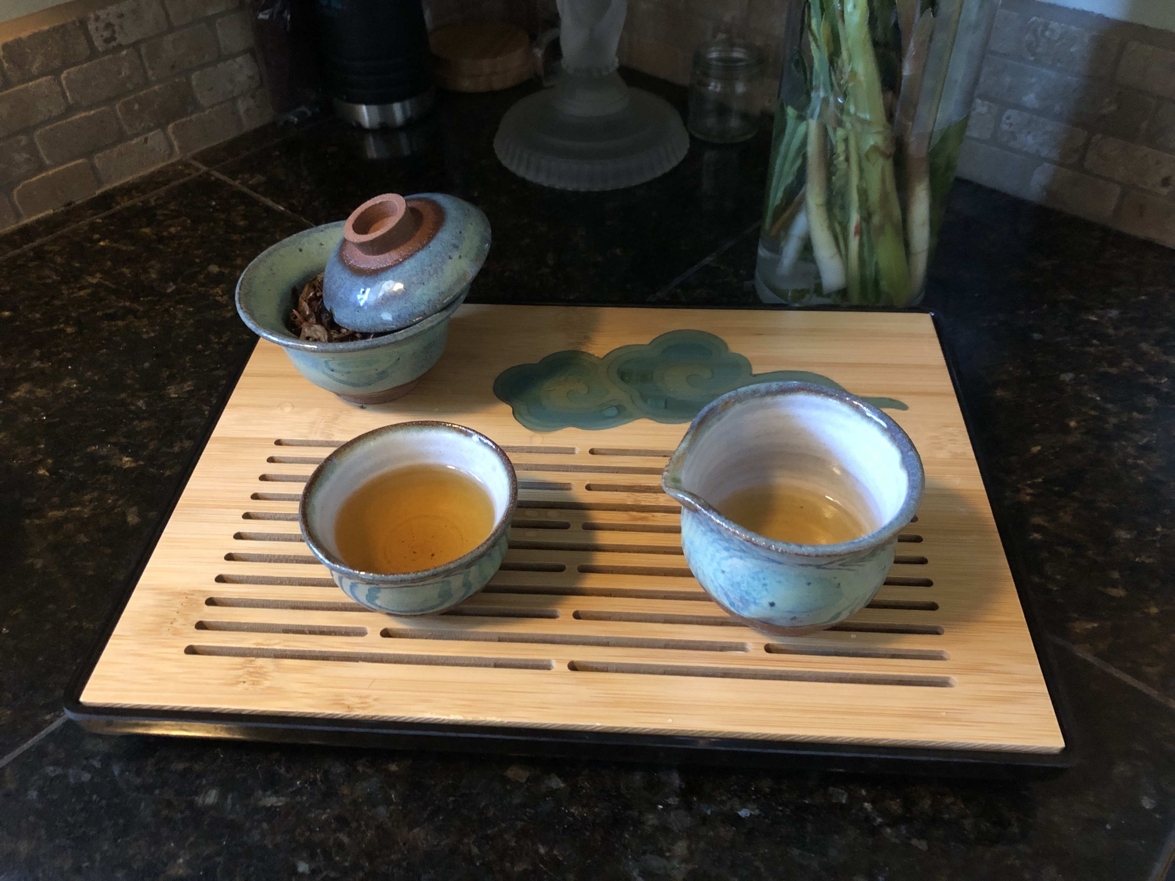 A blue and red stoneware gong-fu tea setup, with matching gaiwan, pitcher, and cup, on a bamboo tray.